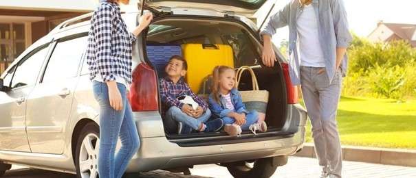 Enfants jouant et dessinant à l'arrière d'une voiture sur la route des vacances, avec un kit d'activités.